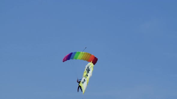 Skydiver Flies on Rainbow Parachute with Hieroglyphs on Flag and Gently Lands.