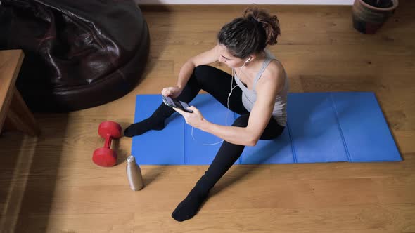 Smiling sportswoman using smartphone at home