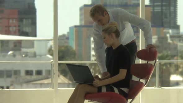 LS OF A BUSINESSMAN AND BUSINESSWOMAN LOOKING AT A LAPTOP