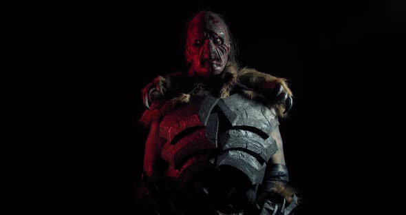 Orc in Metal Armor Is Standing in Dark Red Lighting and Lifting Up a Sword, 