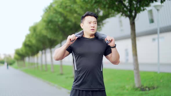 Exhausted after workout training or jogging Asian athlete man standing outdoors 