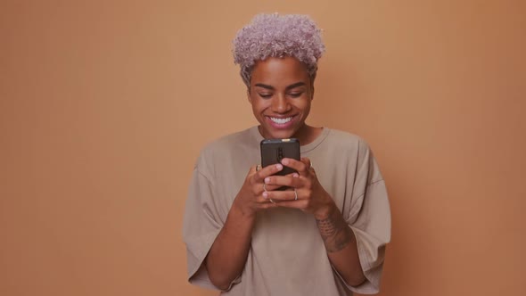 Smiling African Woman Types Text Message on Cell Phone Enjoys Communication