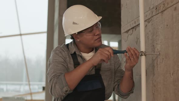 Woman Screwing on Pipe to Wall