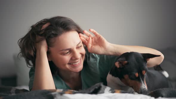 Closeup Shot of a Young Woman Petting Her Basenji Dog While Lying in Bed