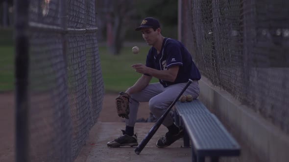 A baseball player resting on the bench.