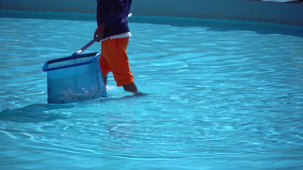 A Man Removes Garbage From the Pool with a Sap