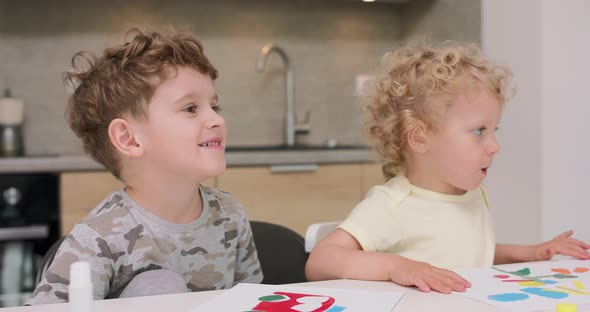 Close Up of a Small Girl and a Small Boy Sitting with Their Father at the Kitchen Table and are