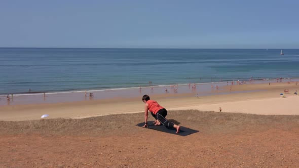 A Middleaged Woman on the Ocean Shore Goes in for Sports Gymnastics