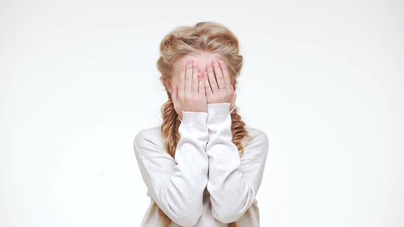 Very Young Beautiful Caucasian Girl with Blonde Long Hair Standing with Face Covered with Hands and