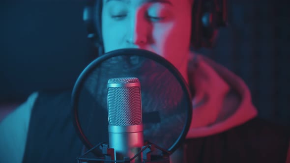 A Man in Hoodie Rapping Through the Pop-filter in the Microphone