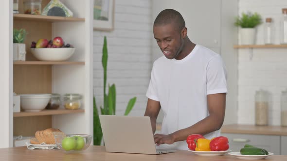 Athletic African Man Doing Video Call on Laptop in Kitchen