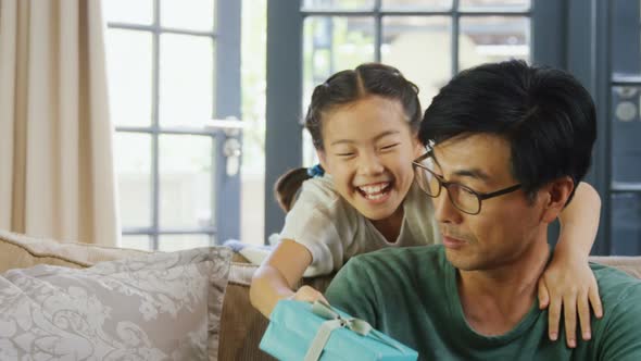 Daughter giving gift box to father in living room 4k