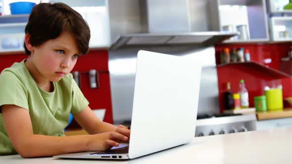 Boy using laptop in kitchen