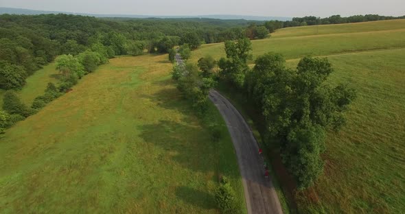 Aerial views of family bicycling along pastoral country roads.