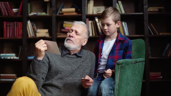 Stylish Grayhaired Grandfather with His Lovely Grandson Enjoy Memories Watching Family Photo Album