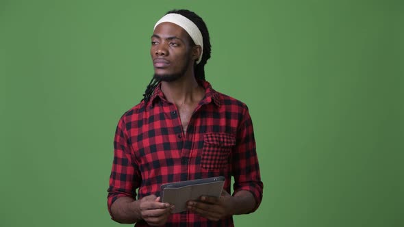 Young Handsome African Man with Dreadlocks Against Green Background