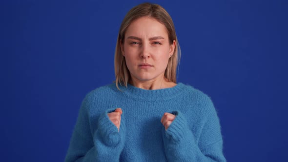 Angry woman wearing blue sweater screaming at the camera