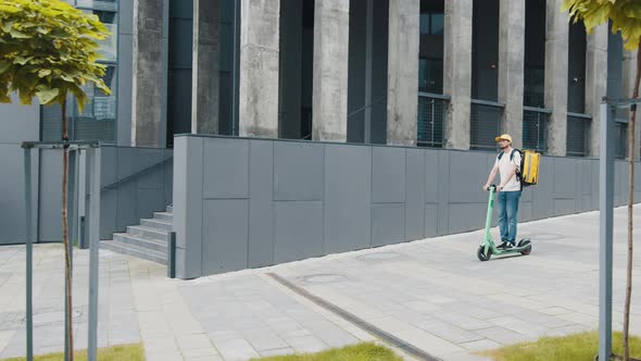 Delivery Boy on Escooter with Backpack Riding Fast on Pavement