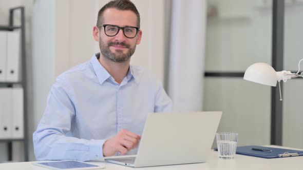 Thumbs Up Sign By Middle Aged Man with Laptop