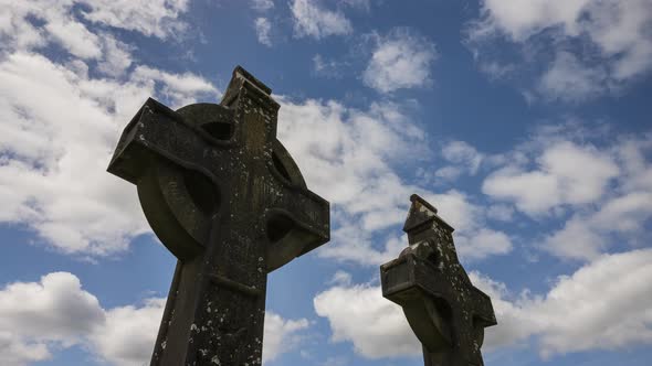 Time lapse of historical cemetery traditional medieval stone cross in rural Ireland with passing clo