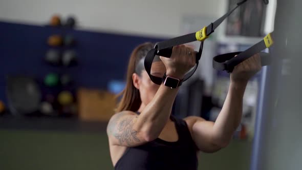 Athletic woman doing cable bicep work on cables in gym