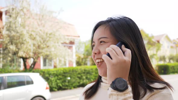 Close up of Asian woman with happy face walking on the road and calling