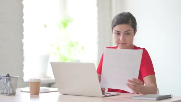 Paperwork By Indian Woman Working on Laptop in Office