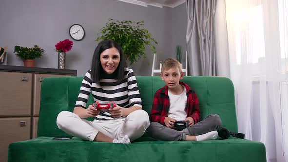 Happy Carefree Mother and Small Son Having Fun Together During Competing Video Racing