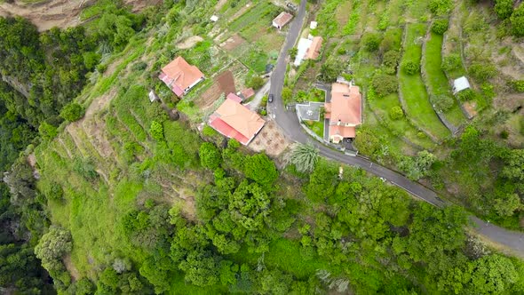 Drone top-down view above waterfall and houses on the edge of a cliff