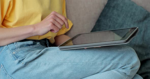 Close Up Woman in a Yellow Tshirt Use the Tablet PC Watching Social Media While Sitting on Sofa in