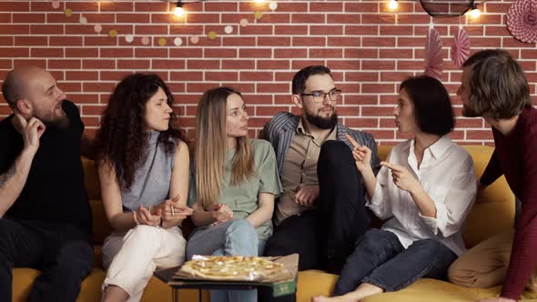 Close Friends are Sitting on the Sofa  Chatting Eating Pizza