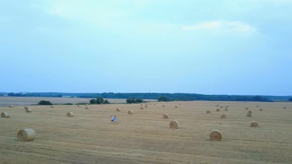 Couple Relaxing On A Field With Hay Bales