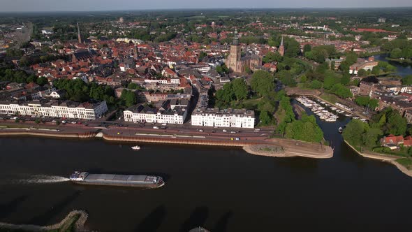 Medieval city seen from above with inland shipping large cargo vessel leaving ripple waves on river