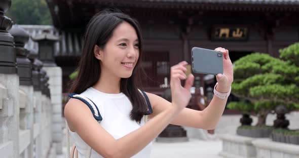 Travel woman use of smart phone to take phone and video in Chinese garden