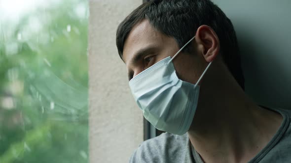 Sad Man in Mask Looks Outside the the Window