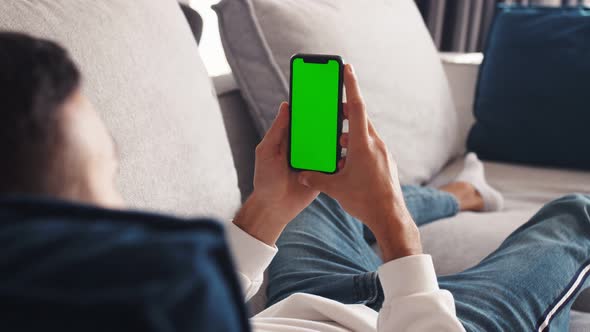 Man Lying on Couch Using Smartphone with Chroma Key Green Screen , Scrolling Various Gestures Like