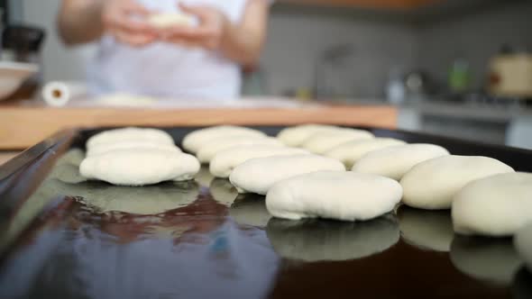 A Woman in the Kitchen Sculpts Pies and Puts Them on a Baking Sheet