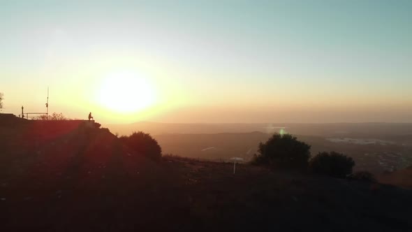 sunset silhouette of person standing on mountain ridge aerial drone 4k