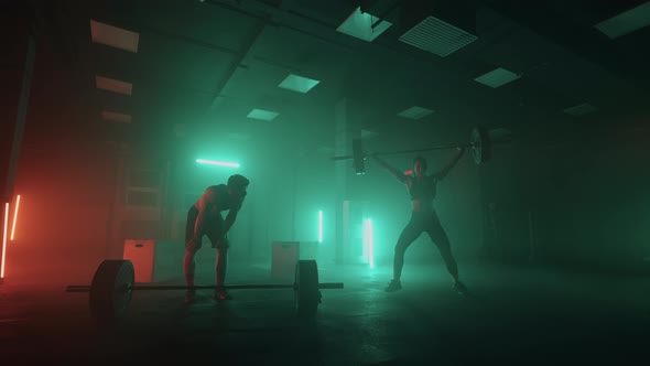 Training of Professional Powerlifters Man and Woman are Lifting Barbell in Dark Gym Sporty People