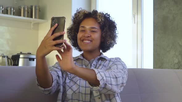 Attractive Teenage Girl Takes Selfies Sitting on the Couch at Home