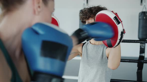 Slow Motion of Female Boxing Trainer Motivating Sportswoman Practising in Gym Together