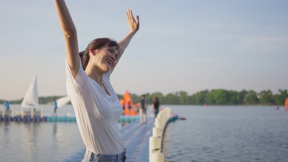 Asian young beautiful woman raising her arms with feel free relaxing on holiday during vacation.