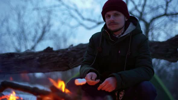 Portrait of Caucasian Hipster Man with Mustache Smiling While Sitting Near Campfire Outside and
