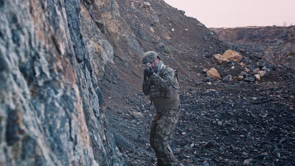 Armed Soldier Walking Over Large Rocks