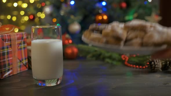 Woman Puts Gingerbread Cookies on a Wooden Table with Milk