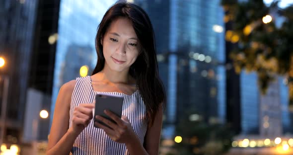 Woman looking at mobile phone in the city of Hong Kong 