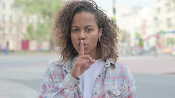 Outdoor African Woman with Finger on Lips Please Be Quiet