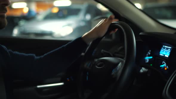 Man is Driving Car Through a Parking Lot and is Looking for a Place to Park