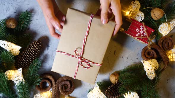 Female Hands Slowly Twist a New Year's Gift on the Background of Various Holiday Trinkets and