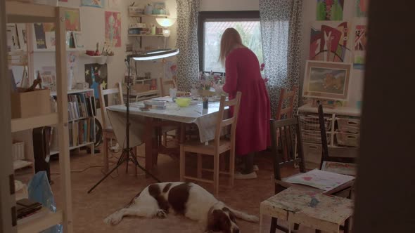 Woman with a Dog is Preparing for an Art Lesson in Her Home Studio
